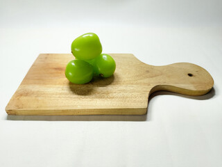 Vibrant green grapes piled neatly on a rustic wooden cutting board, ready for a healthy snack or culinary preparation, showcasing freshness and natural beauty