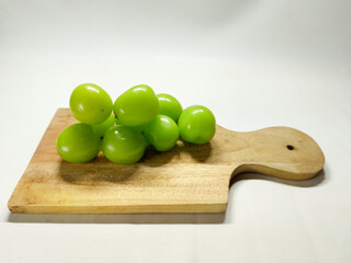 Fresh green grapes arranged on a wooden cutting board, ready for a healthy snack or culinary use