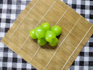 Vibrant green grapes, freshly picked and arranged on a natural bamboo mat, perfect for a healthy and refreshing snack or a gourmet culinary delight