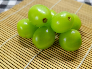 A beautiful arrangement of fresh, organic green grapes, showcasing their plump and juicy nature, resting on a traditional bamboo mat, symbolizing healthy and delicious fruit