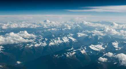 Aerial View of Snow-Capped Mountain Range Under Blue Sky with Clouds