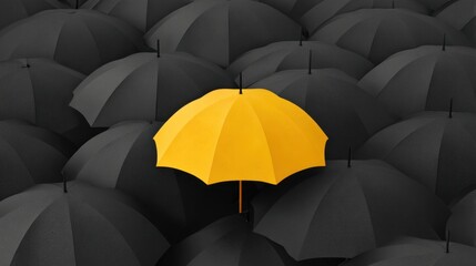 Bright yellow umbrella stands out among dark umbrellas creating a striking contrast in urban environment symbolizing individuality and uniqueness