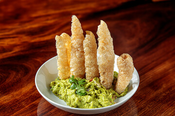 Guacamole avocado dip with Pork Rinds chicharron on a white plate