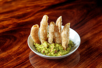 Guacamole avocado dip with Pork Rinds chicharron on a white plate