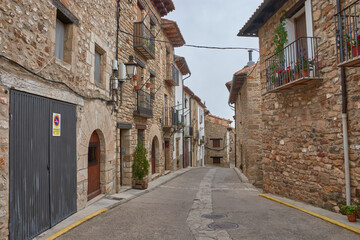 Picturesque alleys of the medieval village of Puertomingalvo, Teruel, with stone houses and flowerpots