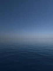 Obraz premium Calm ocean water reflects the tranquil blue sky creating a serene and peaceful seascape on a clear day near the distant horizon line.