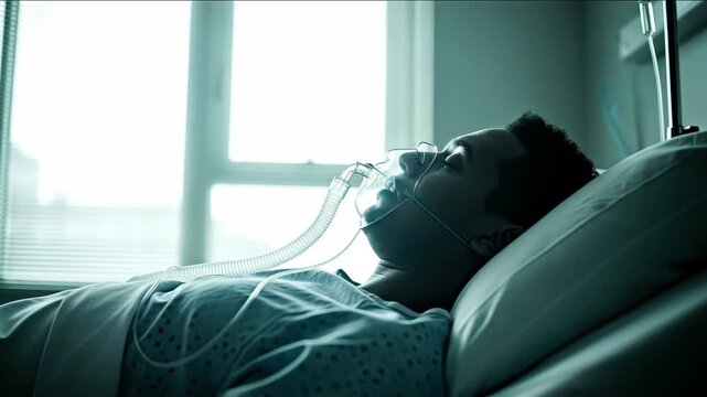 Young male patient with an oxygen mask lying unconscious in a hospital bed