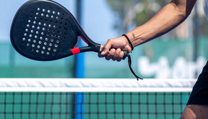 Dynamic sports shot of a man hand holding a padel mid swing on a court, background