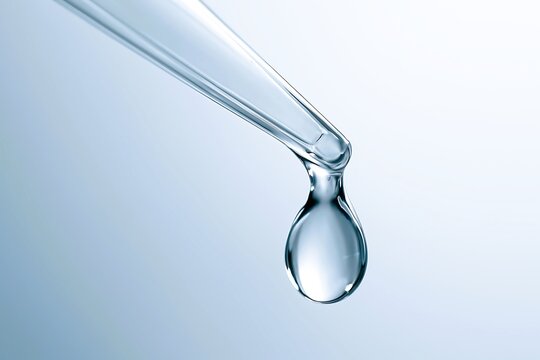 A macro view of a dropper releasing a single liquid droplet, often used in science, medicine, skincare, or chemistry labs.