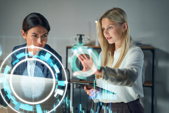 Business Women Analyzing High Tech Security Interface With Holographic Data Visualization In Modern Office