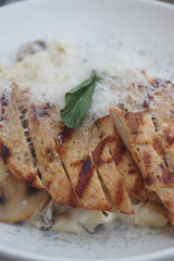 Grilled chicken with creamy pasta and herbs on a plate