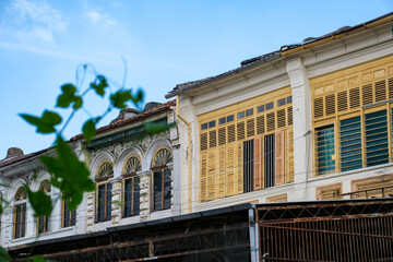 Street view of a row of colorful colonial era shophouses facade in George Town, Penang, Malaysia. The heritage architecture reflects the multicultural history of this UNESCO world heritage site. © JianAnn