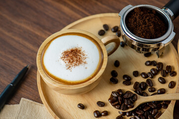 Hot coffee espresso latte with milk froth foam in wood cup. barista pouring milk liquid froth foam...