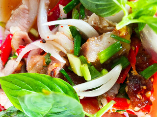Grilled pork with fresh vegetable salad on a black plate. Spicy food