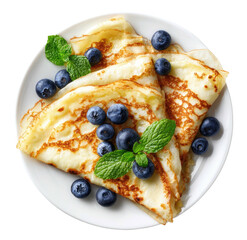 Two golden-brown crepes, topped with fresh blueberries and mint leaves, presented on a white plate