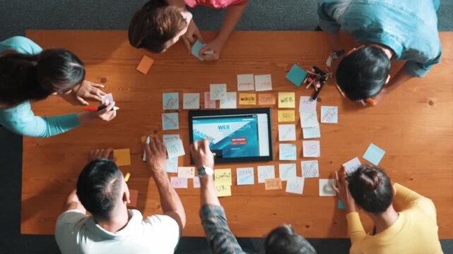 Top down view of programmer brainstorming and planning about web design while looking at tablet wireframe prototype. Aerial view of skilled developer team talking about digital application. Symposium.