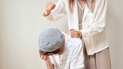 高齢女性を後ろから叩こうとする女性の手