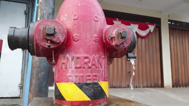 Close-up of a red fire hydrant with water leaking from the nozzle.