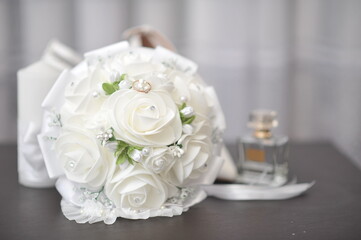 A bouquet of tender blooms cradles a ring upon its petals, while a bottle of fragrant perfume rests beside it, weaving together a scene of love, elegance, and timeless romance.