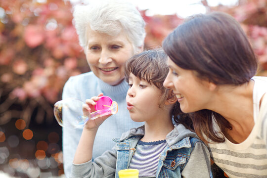 Grandma, mother and child blowing bubbles at park together, love or generation connection in bonding. Outdoor activity, sensory play or women outside for family fun, care or happiness in relationship