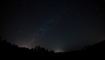 Starry Night Sky Over Dark Silhouetted Landscape at Dawn