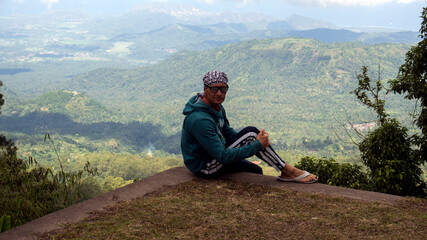 The guy stands against the background of a tropical forest. Adventures in Southeast Asia