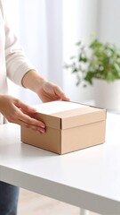 A woman with long brown hair is carefully placing a colorful gift inside a decorative box adorned with ribbons and a cheerful pattern.