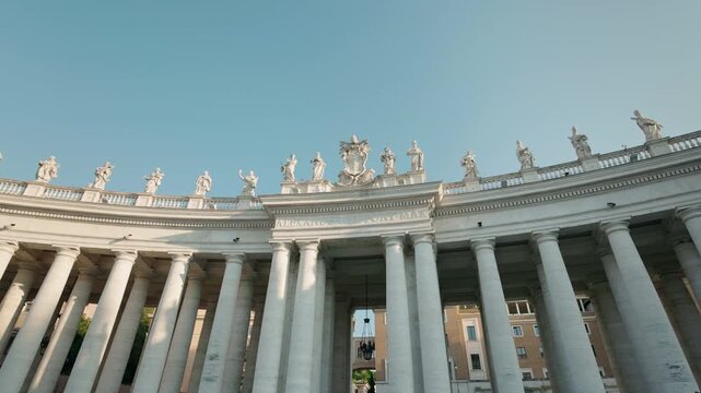 Colonnade of St. Peter's Square with statues of saints and clear blue sky in Vatican City, Rome, Italy