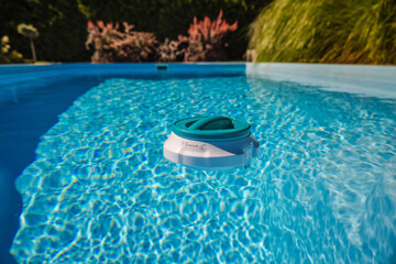 Floating chlorine dispenser with thermometer drifting in a clear outdoor pool, helping maintain clean water and safe swimming conditions