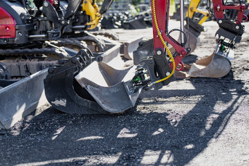 Detailed view of hydraulic excavator attachments with steel digging buckets, hydraulic hoses and...