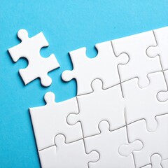 Obraz premium A single white jigsaw piece rests near a partially completed white jigsaw puzzle on a light blue background