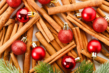 Christmas background with cinnamon sticks and red ornaments.