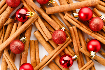 Christmas background with cinnamon sticks and red ornaments.
