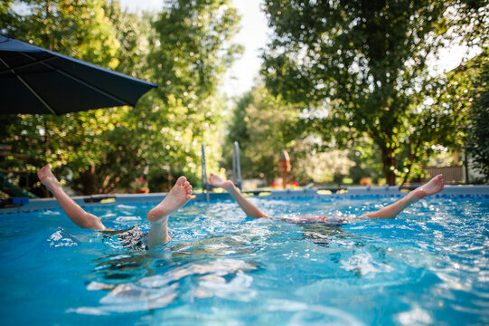 Children playing together in a backyard swimming pool on summer day