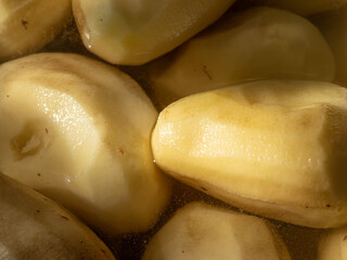 Peeled raw potatoes soaking in water close-up