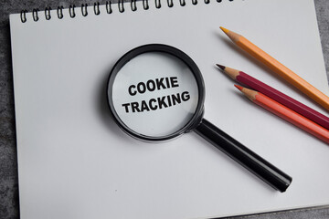 Concept of cookie tracking write on book with magnifying glass isolated on Wooden Table.