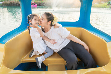 Asian mother and daughter show love on a floating boat.