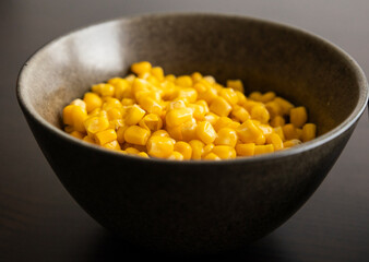 Drained Sweet Corn Kernels in Dark Bowl on Black Background Close-Up
