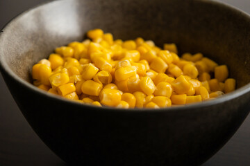Drained Sweet Corn Kernels in Dark Bowl on Black Background Close-Up