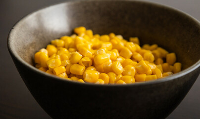Drained Sweet Corn Kernels in Dark Bowl on Black Background Close-Up