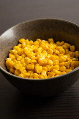 Drained Sweet Corn Kernels in Dark Bowl on Black Background Close-Up