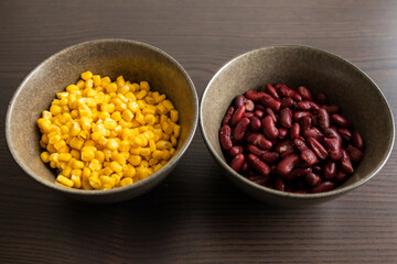 Two Dark Bowls with Drained Corn and Red Beans on Black Background