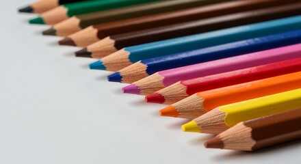 Colorful pencils arranged diagonally on white surface for creative design