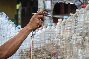 A hand is painting using a compressor paint sprayer.