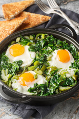 shakshuka green sauce loaded with fresh herbs, spinach, and spices is the perfect foil for rich, runny eggs closeup on the pan on the table. Vertical