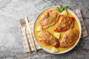 Chicken Saltimbocca is an Italian-inspired dish made with thin chicken cutlets wrapped in prosciutto and sage and lemony white wine sauce closeup on the plate on the table. Horizontal top view