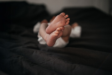 Baby feet in bed, newborn baby feet in gray blanket