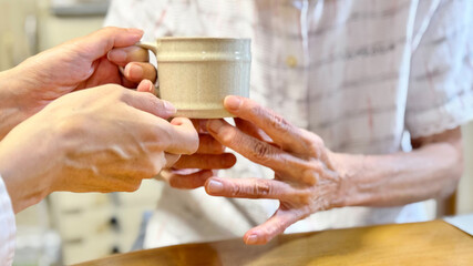 高齢女性に飲み物介助する女性の手