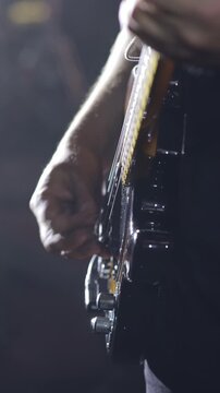Close-up of guitarist playing electric bass guitar live on stage
