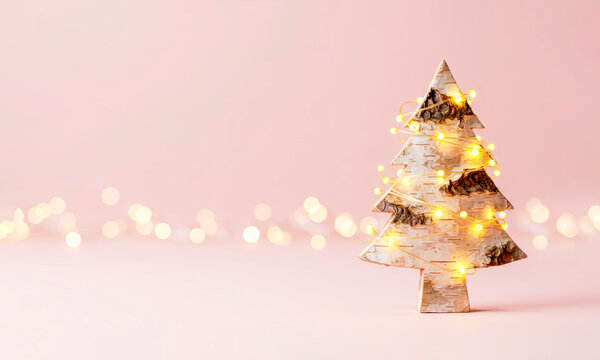 Birch bark Christmas tree with festive golden shining garland on pink background - Powered by Adobe